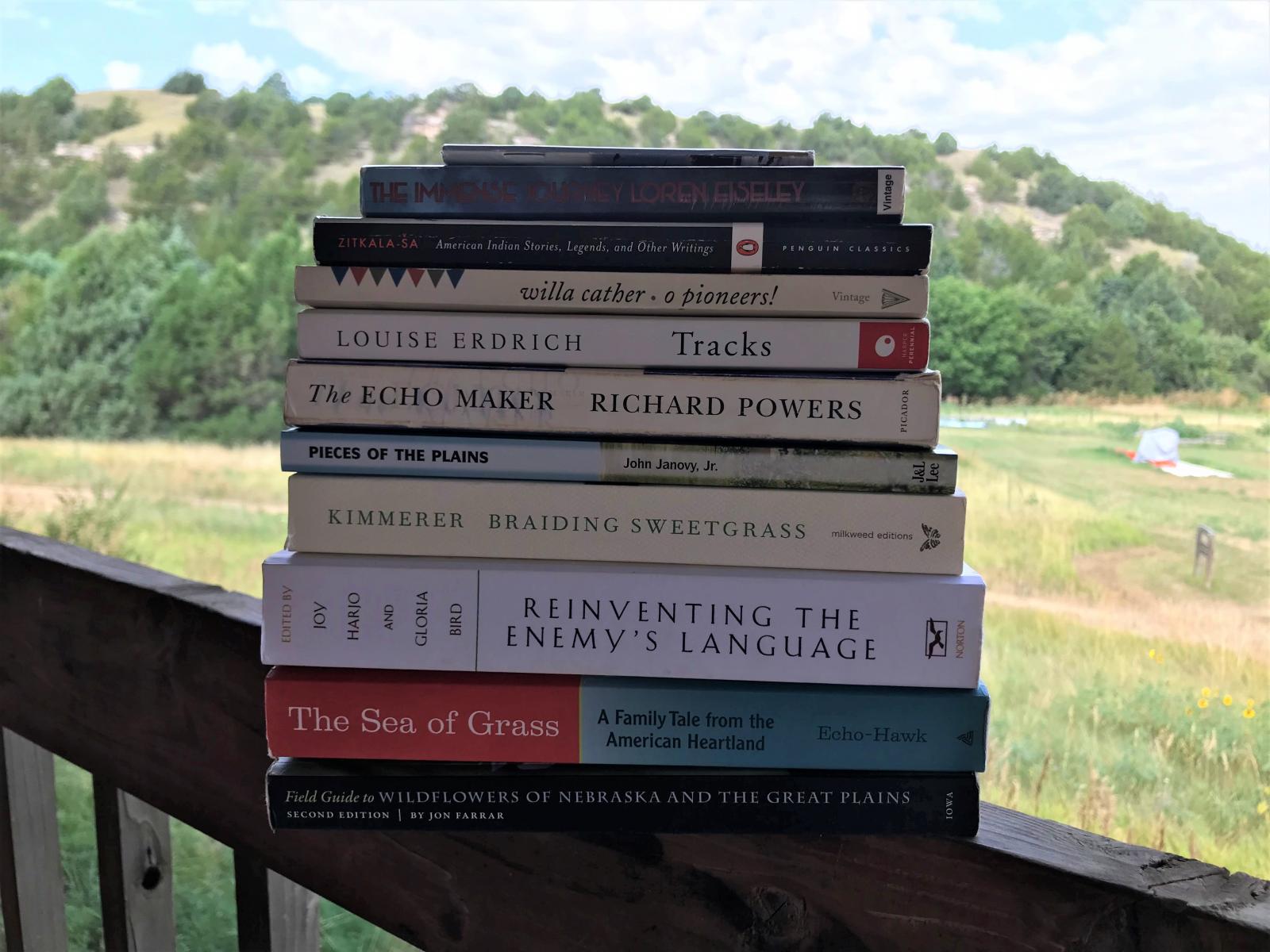 Stack of books on a railing with hills in the background.