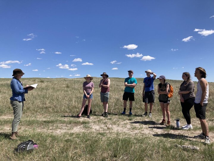 Dr. Rau reading an excerpt to class in the prairie.