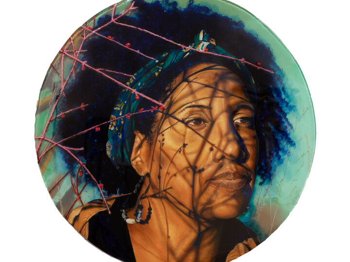 Between Spaces (Charlette Harrington) by Kat Wiese using spray paint, grass, oil, resin on panel. Woman sitting in nature while the sun rises or sets looking out away from audience with budding twigs casting shadows on face.