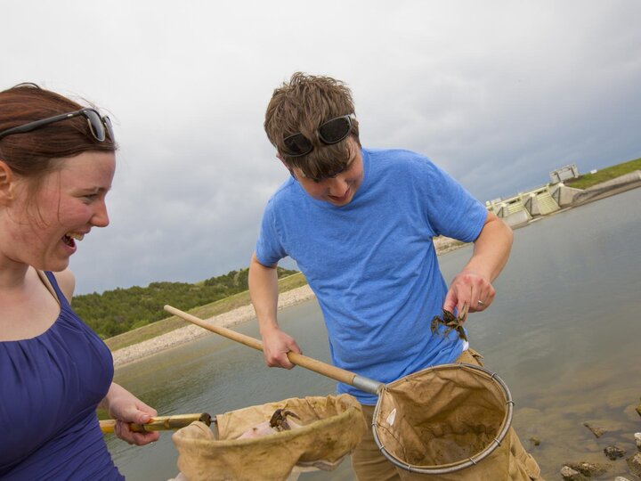 Students collect a crawfish from the water nets